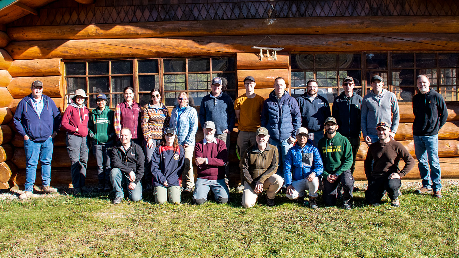group of people standing in front of a log cabin